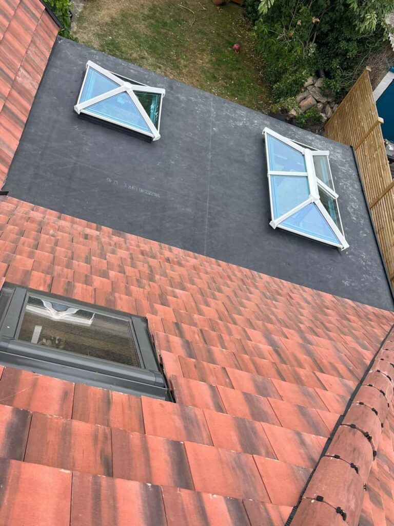This is a photo taken from the roof ridge looking down a tiled pitched roof on to a flat roof. Works carried out by Swanmore Roofing Repairs